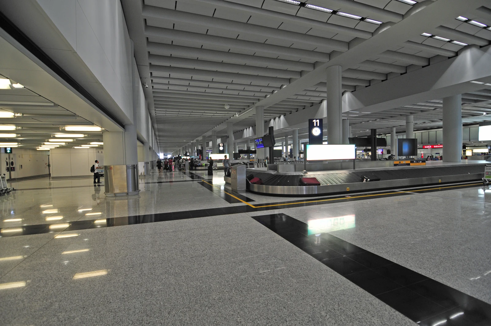 A baggage reclaim carousel and travellers at Hong Kong International Airport