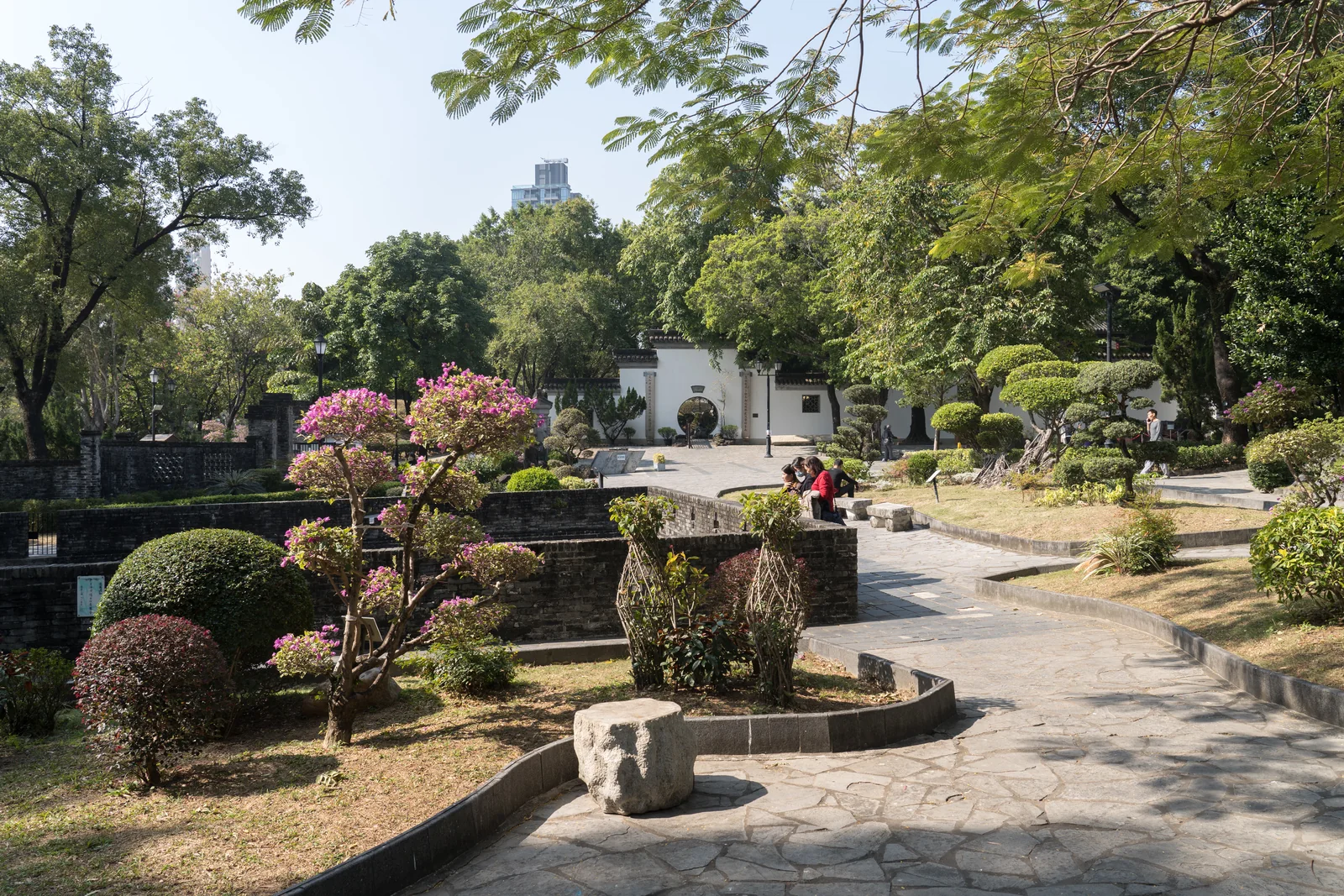 九龍寨城公園的園路、樹木與白牆圓洞門