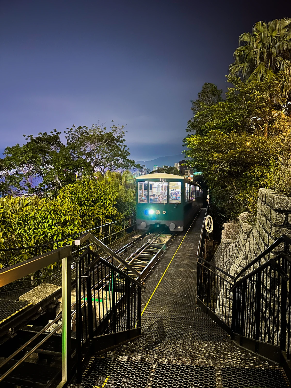 A green Peak Tram on hillside rails at night