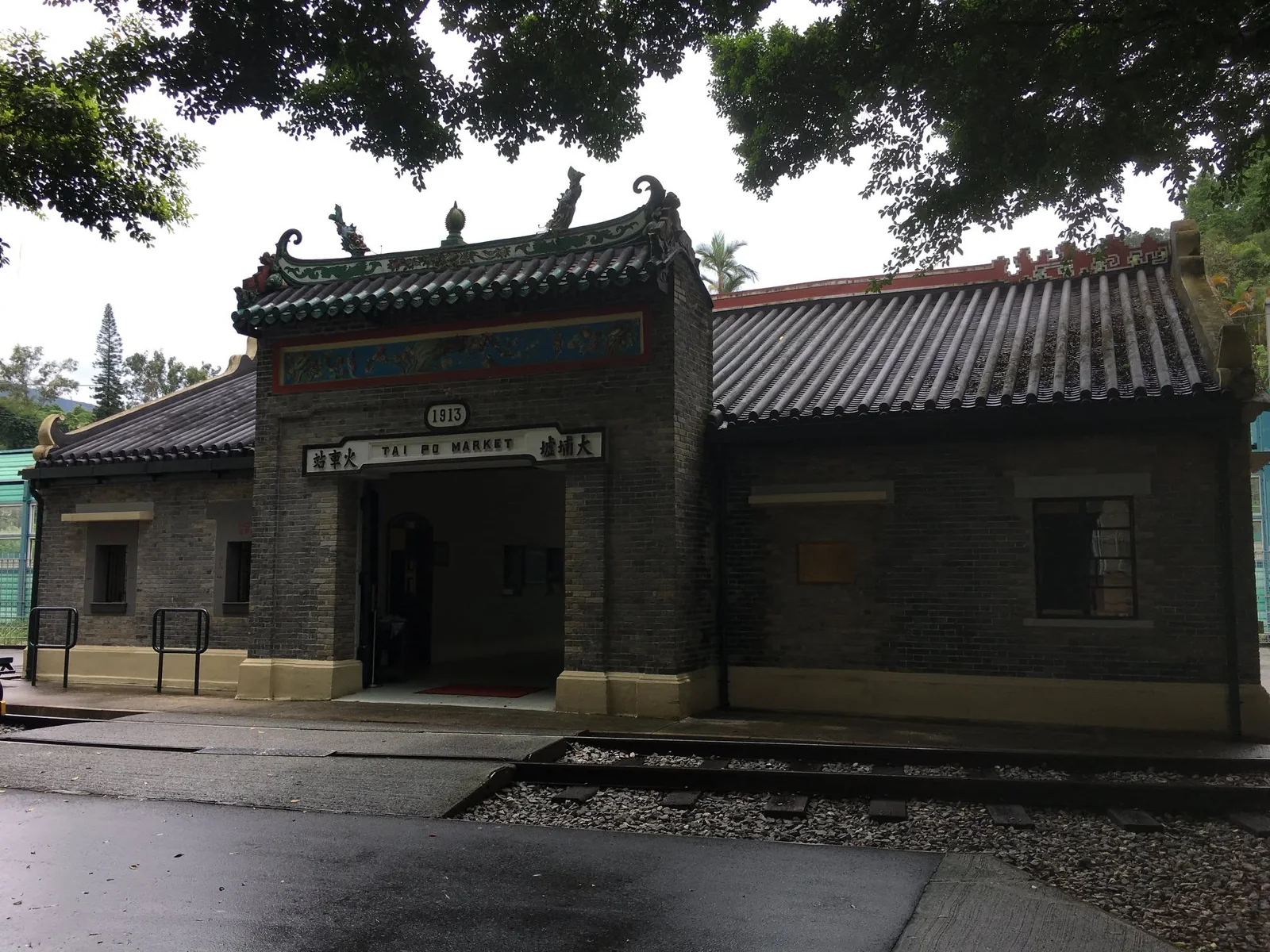 Frontage, roof and tracks of the old Tai Po Market station in shade
