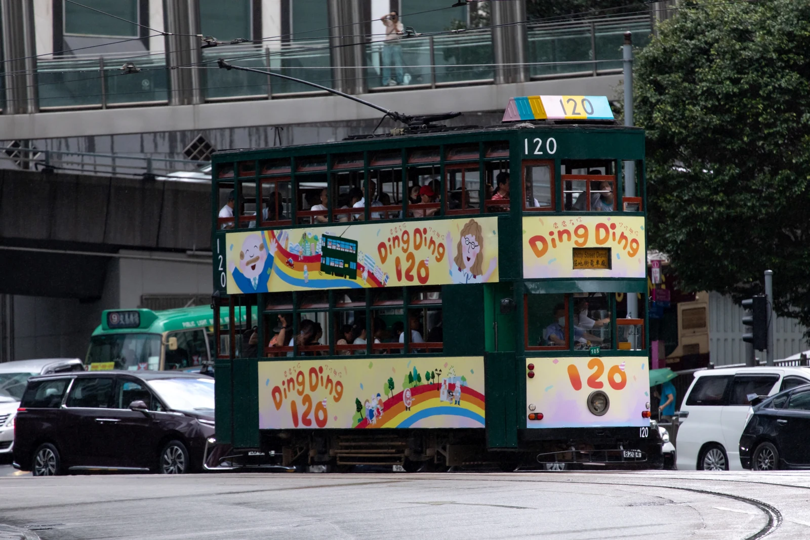 Green Hong Kong tram 120 travelling along a street