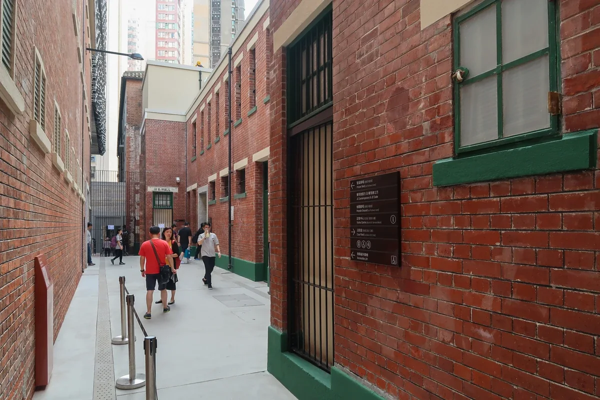 Red-brick buildings and green doors outside A Hall at Tai Kwun